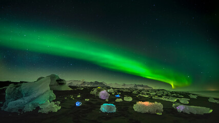 aurora borealis on a beach with icebergs