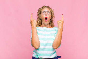 Middle age woman feeling awed and open mouthed pointing upwards with a shocked and surprised look