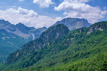 Summer landscape – Albanian mountains, covered with green trees, clouds on blue sky.