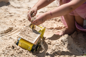 Child playing in a sandbox with a toy