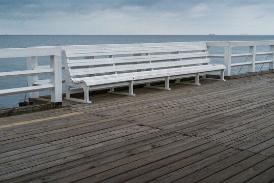 Empty Bench On Wooden Boardwalk At Seashore