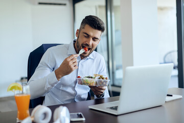 Young entrepreneur enjoying in healthy food while having lunch break in the office.