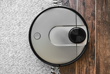 Top view of Robot vacuum cleaner on the edge of carpet and wood floor, Smart robotic automation...