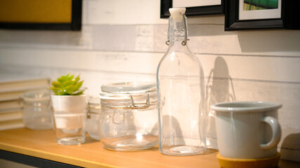 Glass of water with a bottle on table. Clear glass bottles and containers of various sizes and shapes.
