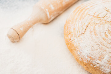 close up view of fresh baked bread and wooden rolling pin on flour