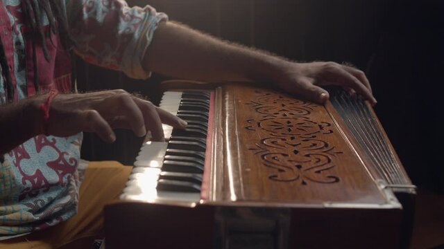 Hindi world. Creative people. Close up of an Indian man playing traditional instrument in the sound studio. Male person plays meditation music.