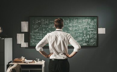 Mathematician reviewing math formulas on the chalkboard