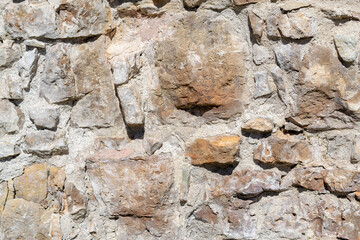 Naklejka premium Uneven, old, rough, irregular granite stone wall. Natural textured background.
