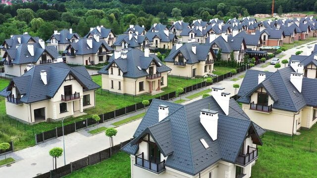 Aerial drone point of view of residential district with modern private houses. Flying over moving black car driving along mansions in countryside area.