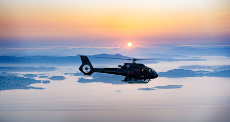 Helicopter flying over to the backdrop of a beautiful sunrise