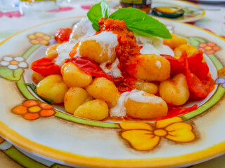 Piatto di gnocchi di patate con pomodorini, burrata siciliana e basilico fresco