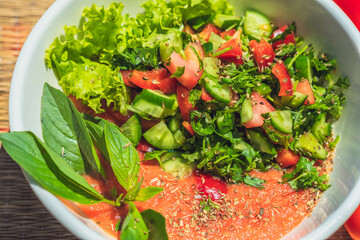 Raw vegan salad with green leaves mix vegetables in white bowl. Cooking recipe blended tomato...