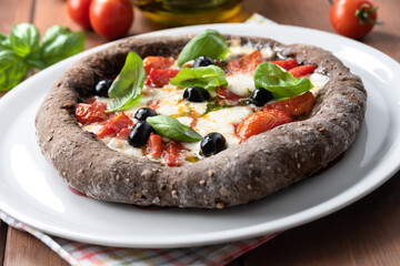 Pizza nera ai sette cereali con mozzarella, pomodorini, olive e basilico, Cucina Italiana