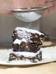 Palha italiana sendo preparada, doce brasileiro feito com brigadeiro, biscoitos de amido de amido e açúcar de confeiteiro.