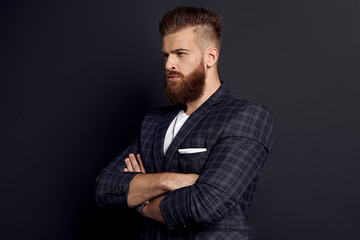 Fototapeta premium Handsome man keeping arms crossed while standing in profile against grey background