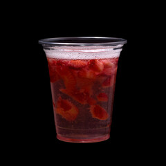 Strawberry cocktail isolated on a black background. Drink in a plastic glass.