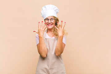 middle age woman baker smiling and looking friendly, showing number nine or ninth with hand...