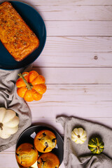 Thanksgiving background. Wooden plank background. Baked goods: loaf of bread, muffins and pumpkins on linen napkins. Cozy fall vibe.