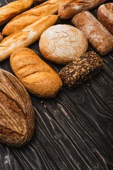 Fotobehang fresh baked bread loaves on wooden black surface © LIGHTFIELD STUDIOS