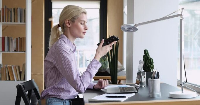 Serious 35s businesswoman sit at desk in modern office solve issue with client by speaker phone. Student prepare for exams using cellphone talk with mate using loudspeaker easy convenient device usage