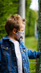 Obraz premium Little boy playing in the park with a mask due to the covid-19 pandemic