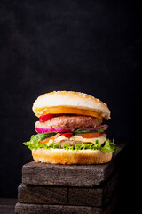 Classical burger with tomatos, beef, cheddar, salat, fresh cucumber and ketchup on wooden background with copy space, isometric vertical orientation