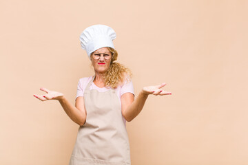 middle age woman baker shrugging with a dumb, crazy, confused, puzzled expression, feeling annoyed...