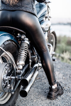A woman in leather leggings is sitting on a motorcycle.