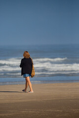 Fototapeta na wymiar Woman walking on a beach next to the ocean in Oregon