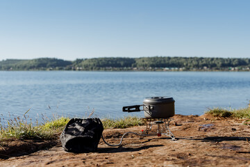 cooking on a gas burner in nature, gas camping stove for cooking food, aluminum pot with a lid...