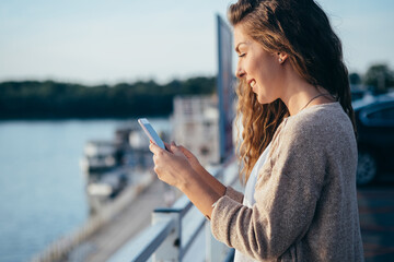 Naklejka premium Smiling young woman looking in mobile phone