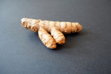 whole turmeric root on a black background side view . kitchen herbs
