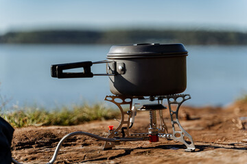 cooking on a gas burner in nature, gas camping stove for cooking food, aluminum pot with a lid...