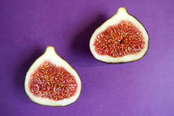 two halves of ripe juicy figs on a lilac background top view. healthy sweet fruits with antioxidants