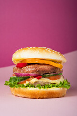 Fresh juicy beef hamburger placed on creative pink background with copy space, isometric vertical orientation