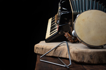 Fototapeta na wymiar Old accordion, tambourine and triangle on rustic wooden surface with black background and Low key lighting, selective focus.