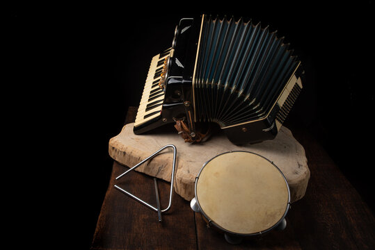 Old accordion, tambourine and triangle on rustic wooden surface with black background and Low key lighting, selective focus.