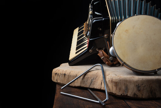 Old accordion, tambourine and triangle on rustic wooden surface with black background and Low key lighting, selective focus.