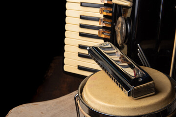 Old accordion, harmonica and bong on rustic wooden surface with black background and Low key...