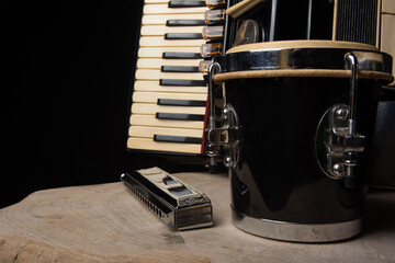 Old accordion, harmonica and bong on rustic wooden surface with black background and Low key...