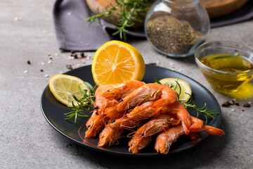 Shrimps on stone background. Grilled prawns with rosemary and lemon. 
