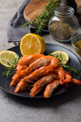 Shrimps on stone background. Grilled prawns with rosemary and lemon. 