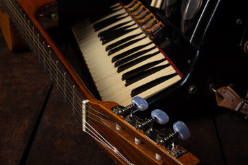Old accordion and a beautiful guitar composing a scene on a rustic wooden surface with black background and low key lighting, selective focus.