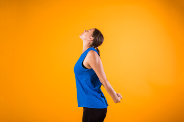 a beautiful woman in a sports uniform does a neck warm-up on an orange isolated background