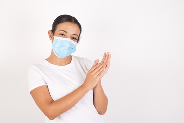 Young arab woman wearing medical mask standing over isolated white background clapping and applauding happy and joyful, smiling proud hands together.