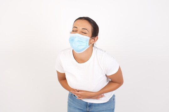 Young arab woman wearing medical mask standing over isolated white background smiling and laughing hard out loud because funny crazy joke with hands on body.