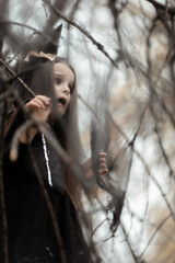 Little girl dressed in a witch costume walking in fall forest with fear expressions. Halloween horror. Witches in darkness
