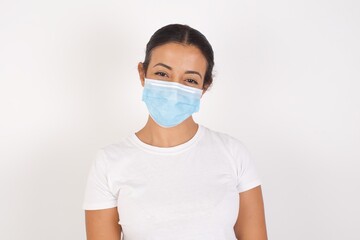 Young arab woman wearing medical mask standing over isolated white background with a happy and cool smile on face. Lucky person.