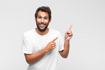 young latin handsome man pointing to self with a confused and quizzical look, shocked and surprised...