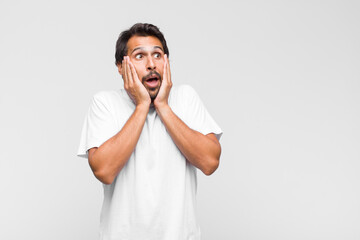 young latin handsome man feeling disgusted, holding nose to avoid smelling a foul and unpleasant...